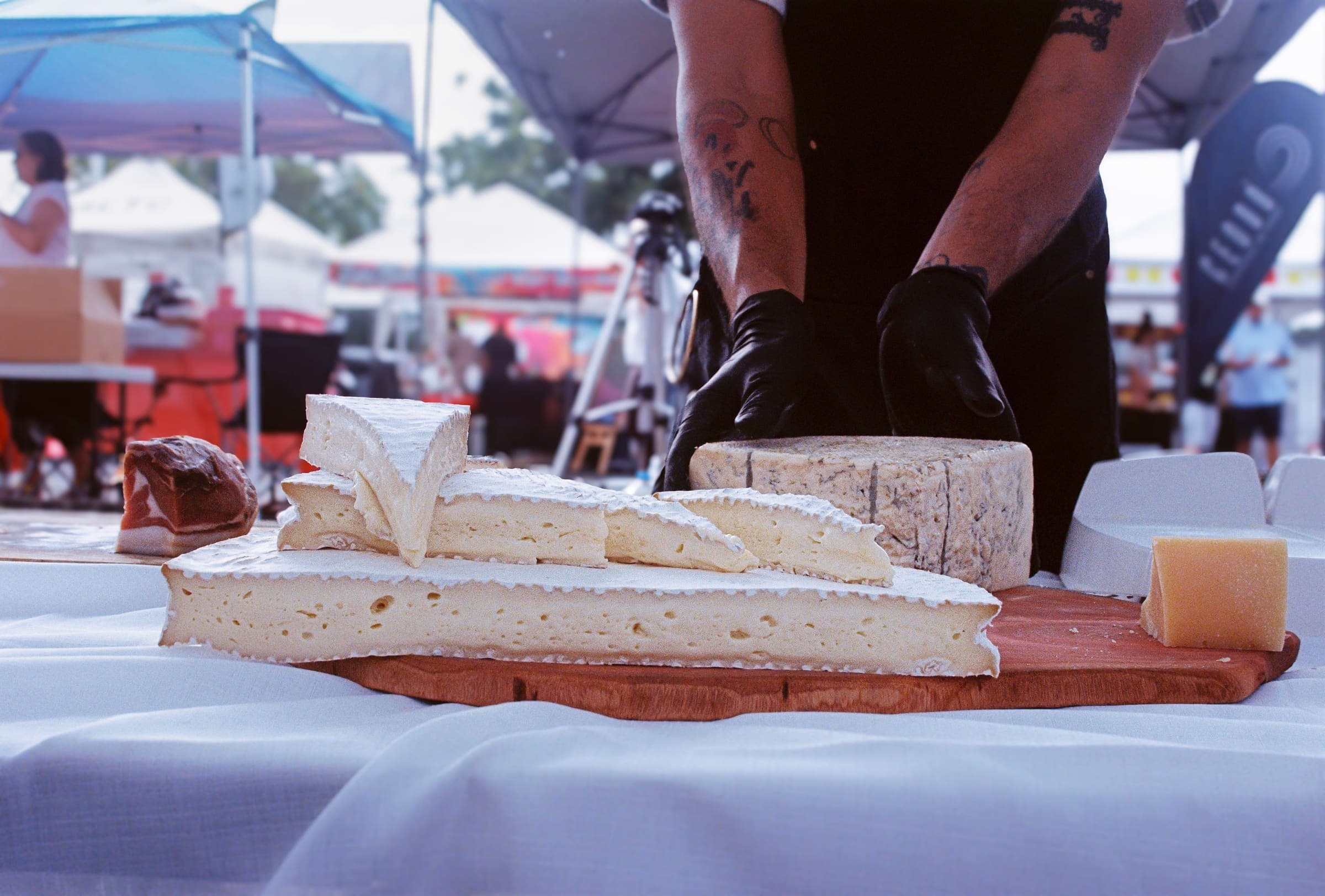 Cutting a wheel of cheese to order at the CUAJADO booth